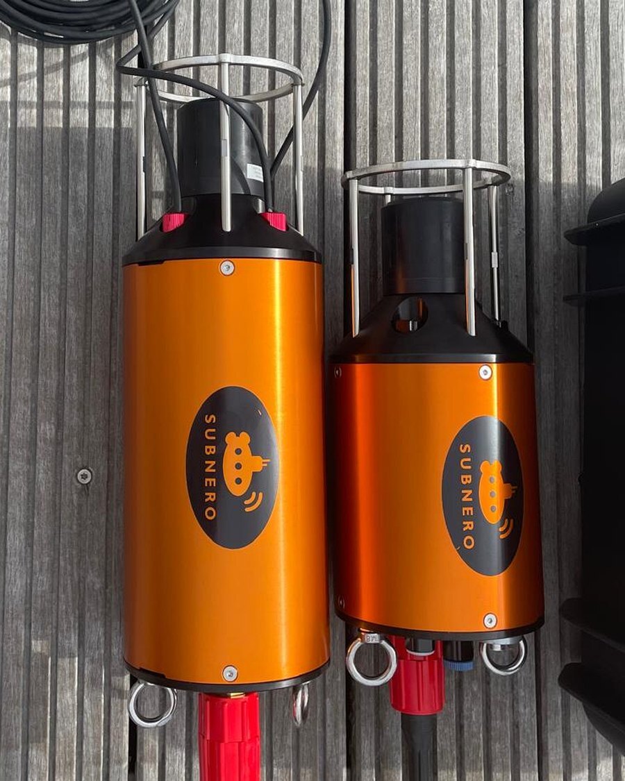 Two orange underwater acoustic modems on a wooden deck